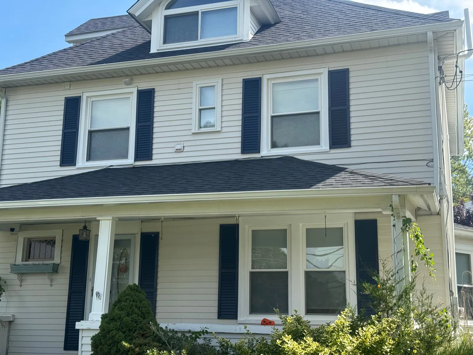 Two-story home with gray siding, white trim and navy shutters in Connecticut
